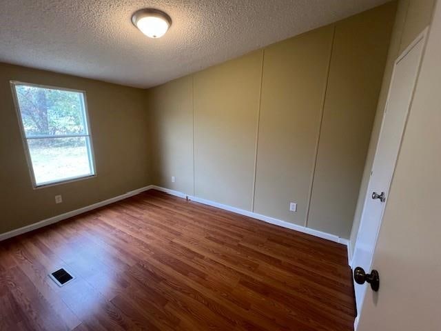 empty room with dark hardwood / wood-style floors and a textured ceiling