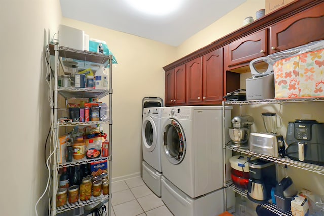 laundry room with light tile patterned floors, washing machine and dryer, and cabinets