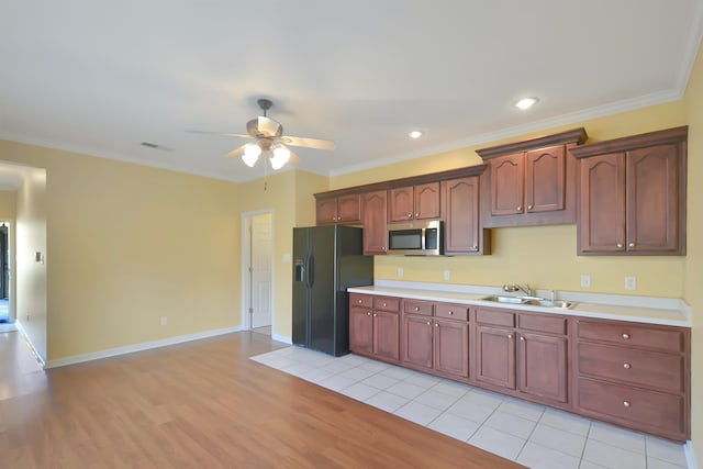 kitchen featuring ornamental molding, sink, light wood-type flooring, and black fridge