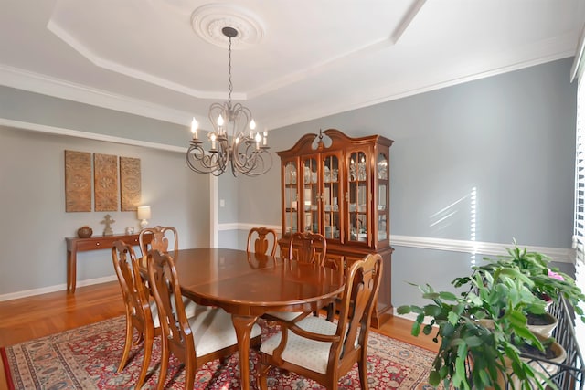 dining room with crown molding, hardwood / wood-style flooring, a chandelier, and a tray ceiling