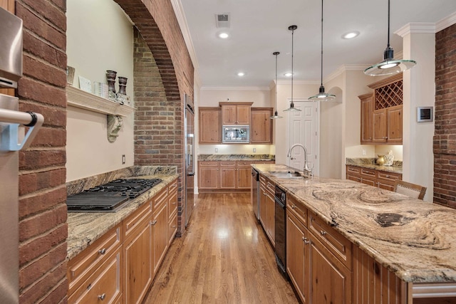 kitchen with brick wall, sink, hanging light fixtures, and stainless steel appliances