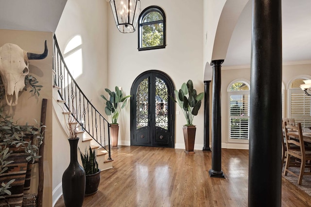 foyer with crown molding, decorative columns, wood-type flooring, and plenty of natural light