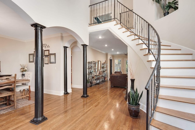 foyer entrance featuring crown molding, wood-type flooring, and ornate columns