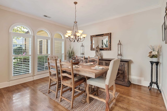 dining area with crown molding, a notable chandelier, and wood-type flooring