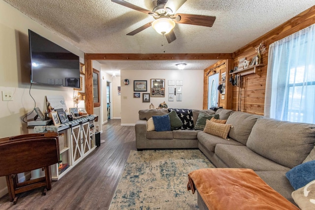 living room featuring a textured ceiling, beamed ceiling, dark wood-type flooring, and ceiling fan