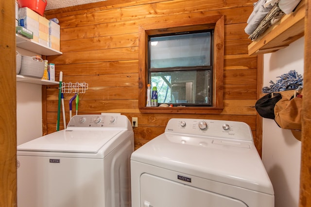 laundry room with wooden walls and washer and dryer