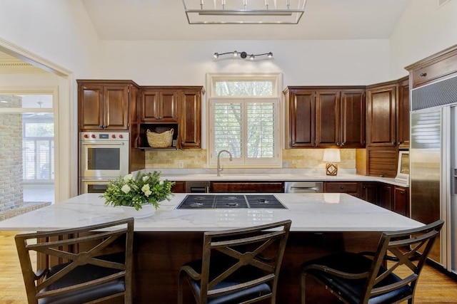 kitchen featuring a kitchen breakfast bar, stainless steel appliances, a center island, light hardwood / wood-style floors, and tasteful backsplash