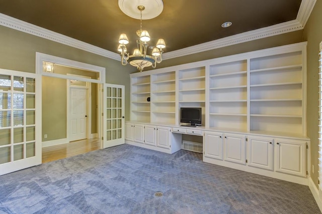 unfurnished office featuring built in desk, crown molding, a notable chandelier, and dark carpet