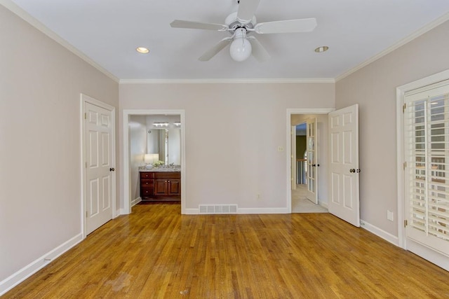 unfurnished bedroom featuring crown molding, ensuite bathroom, and light wood-type flooring