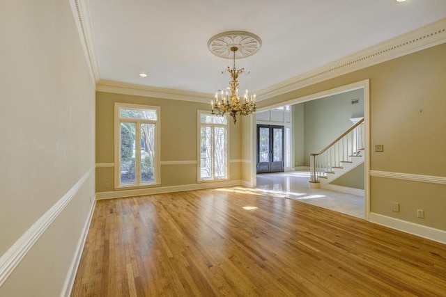 spare room featuring ornamental molding, french doors, a notable chandelier, and light hardwood / wood-style floors