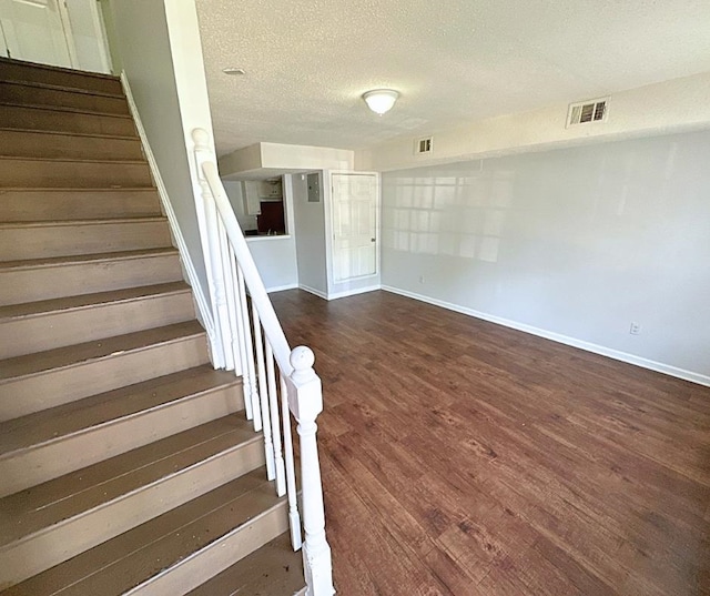 staircase featuring hardwood / wood-style flooring and a textured ceiling