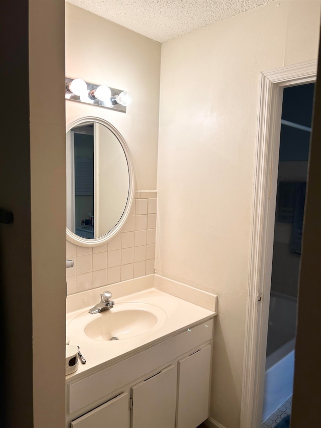 bathroom featuring vanity, a textured ceiling, and decorative backsplash