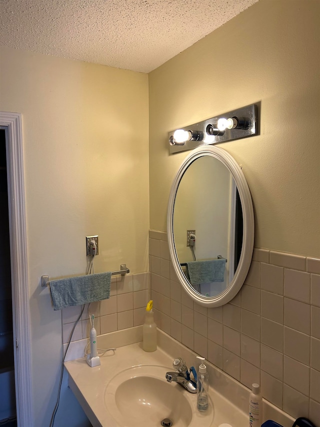 bathroom with sink, a textured ceiling, and tasteful backsplash