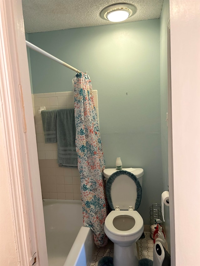 bathroom with toilet, a textured ceiling, tile patterned floors, and shower / tub combo