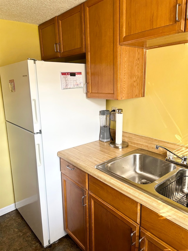 kitchen with white fridge, a textured ceiling, and sink