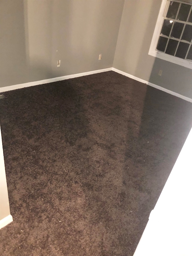 unfurnished room with dark carpet