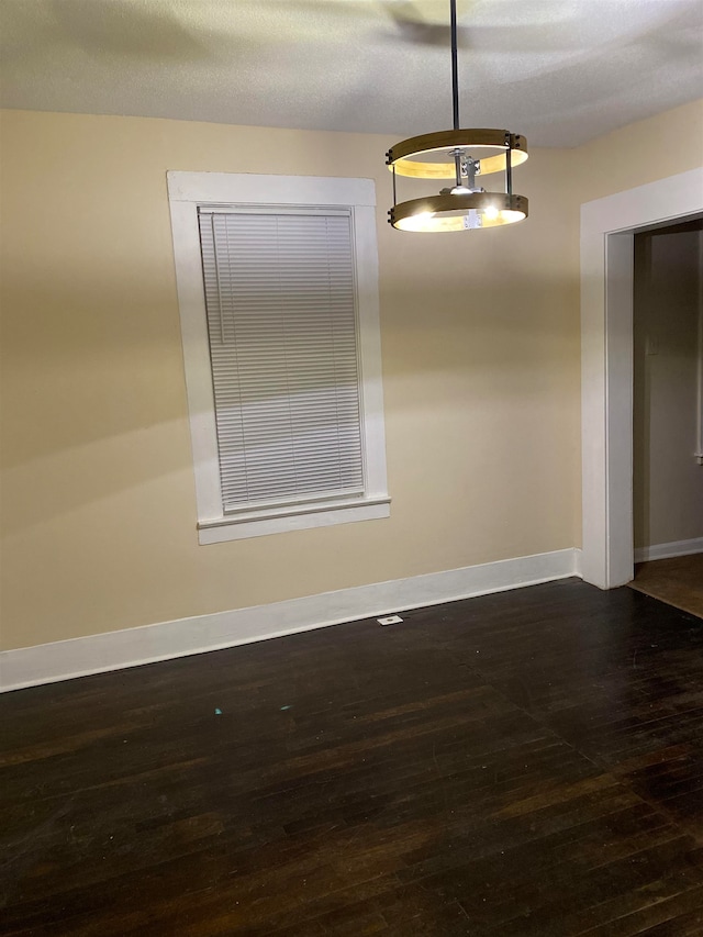 unfurnished room with a textured ceiling and dark hardwood / wood-style floors