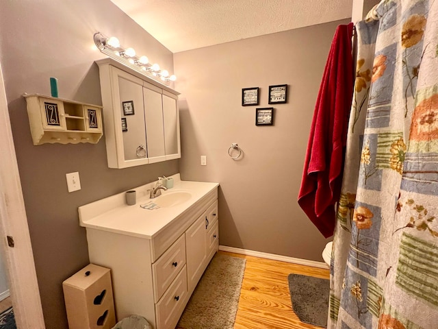 bathroom featuring vanity, a textured ceiling, hardwood / wood-style flooring, and toilet