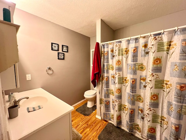 bathroom with a textured ceiling, hardwood / wood-style flooring, toilet, vanity, and a shower with shower curtain