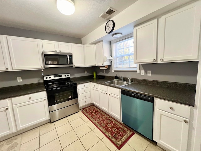 kitchen featuring sink, white cabinets, stainless steel appliances, and light tile patterned floors