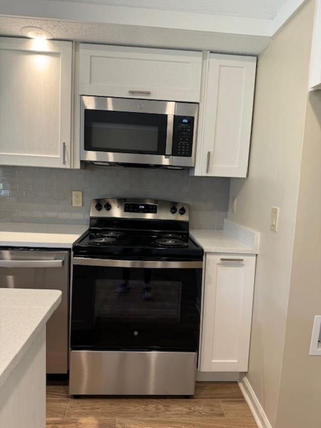 1231 Chamberlain Dr Unit 1231, Memphis, TN 38119 - kitchen with light wood-type flooring, white cabinetry, tasteful backsplash, and stainless steel appliances