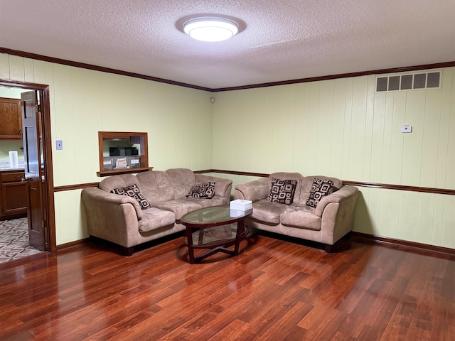 living room with ornamental molding, dark wood-type flooring, a textured ceiling, and wooden walls