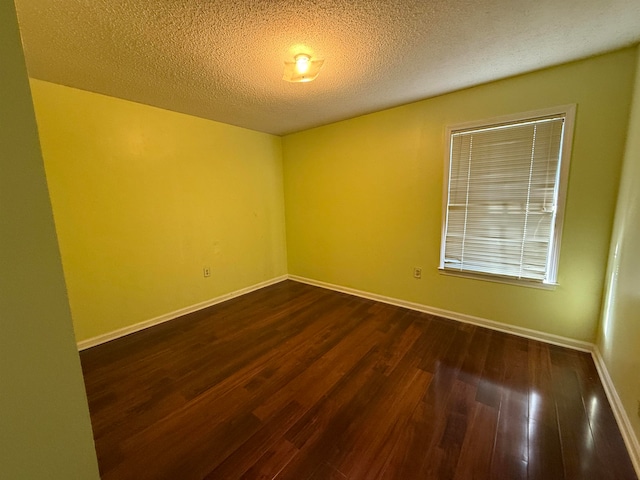 empty room with dark hardwood / wood-style floors and a textured ceiling