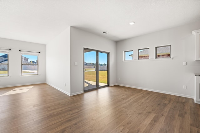 unfurnished room with a textured ceiling and dark hardwood / wood-style flooring