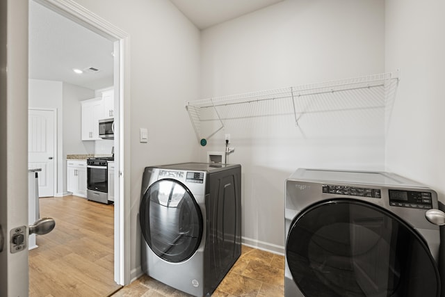 laundry room with light wood-type flooring and separate washer and dryer