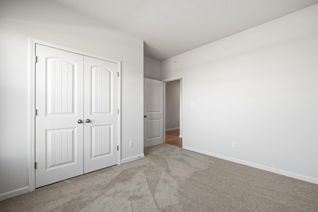 unfurnished bedroom with light colored carpet and a closet