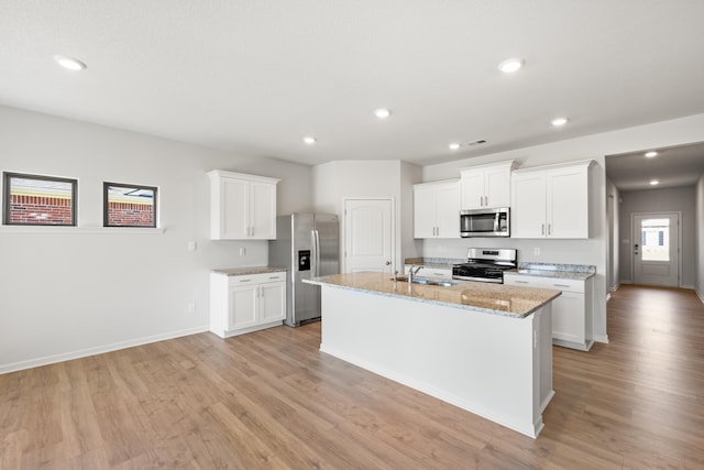 kitchen featuring white cabinetry, light hardwood / wood-style floors, appliances with stainless steel finishes, and a center island with sink