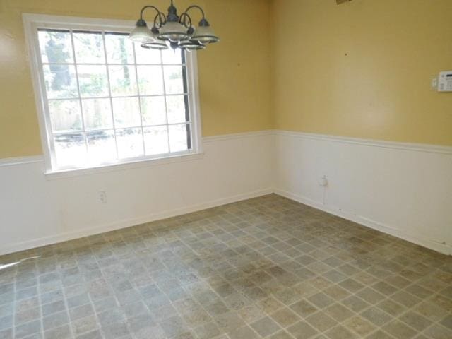 empty room with a healthy amount of sunlight and a chandelier