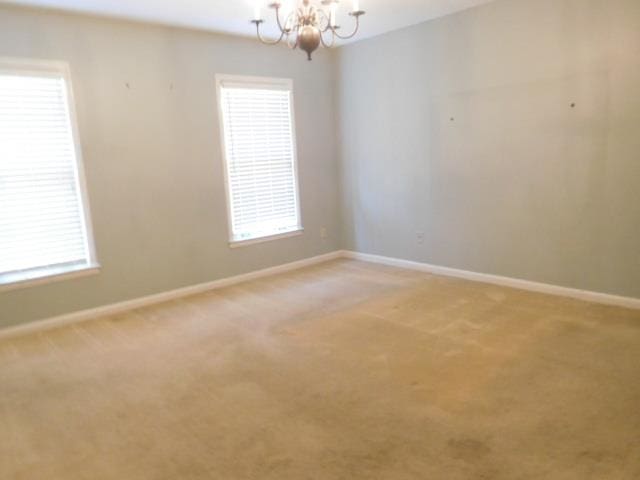 spare room featuring an inviting chandelier, carpet floors, and a wealth of natural light