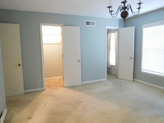 unfurnished bedroom featuring light carpet, a closet, and a chandelier