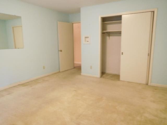 unfurnished bedroom featuring light carpet and a closet