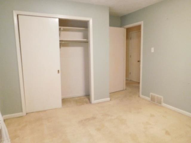 unfurnished bedroom with a closet and light colored carpet