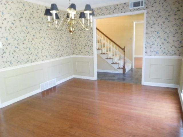 empty room with dark wood-type flooring and an inviting chandelier