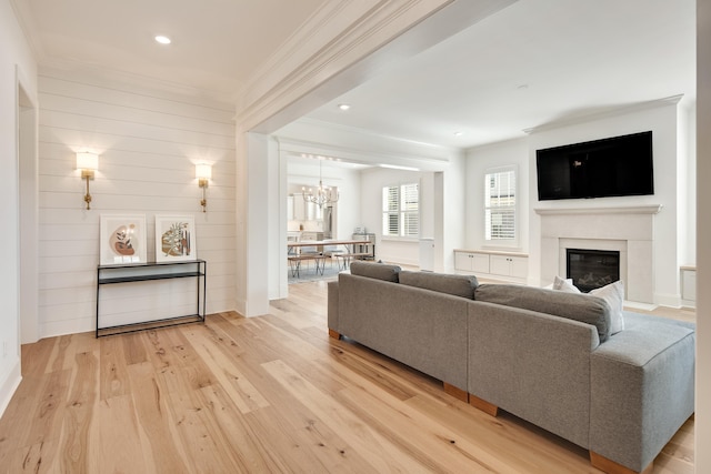 living room with crown molding, a notable chandelier, and light wood-type flooring