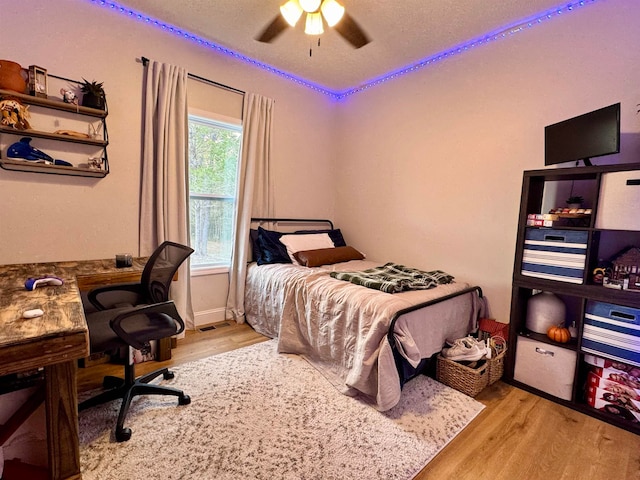 bedroom with light wood-type flooring, ceiling fan, and a textured ceiling