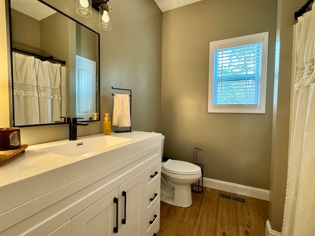 bathroom with a textured ceiling, toilet, vanity, and hardwood / wood-style flooring