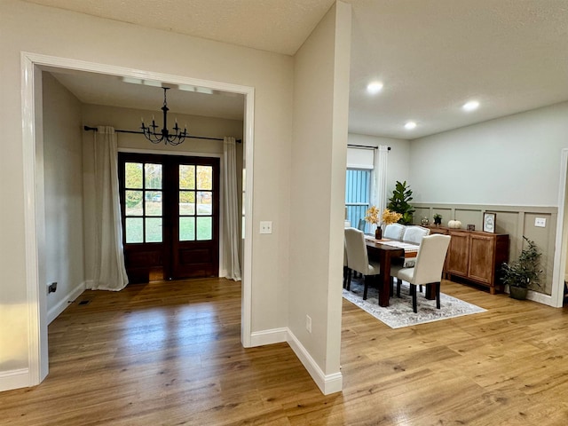 foyer with french doors, light hardwood / wood-style floors, and a chandelier