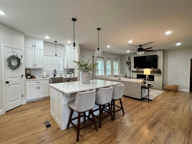 kitchen featuring white cabinetry, a center island, a breakfast bar, tasteful backsplash, and pendant lighting