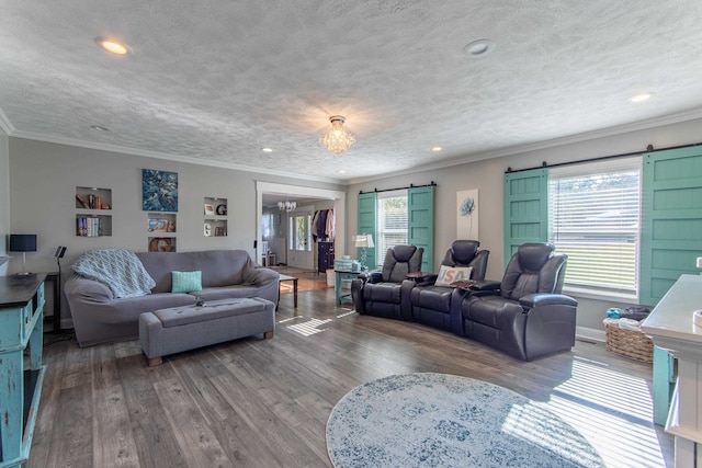 living room featuring hardwood / wood-style floors, a notable chandelier, a textured ceiling, a barn door, and crown molding