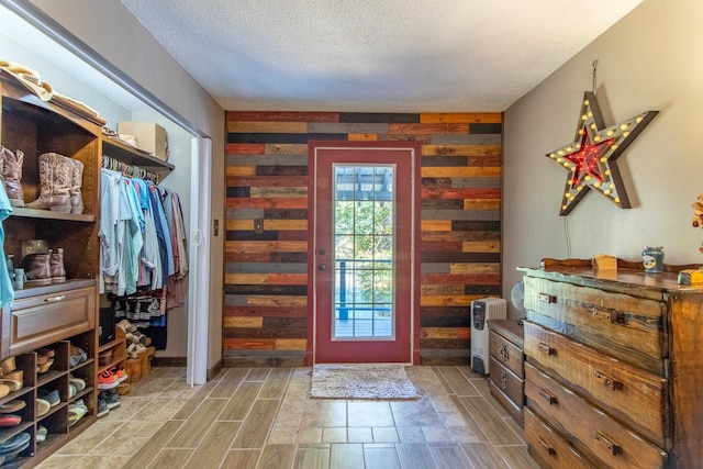 doorway to outside with wood walls and a textured ceiling