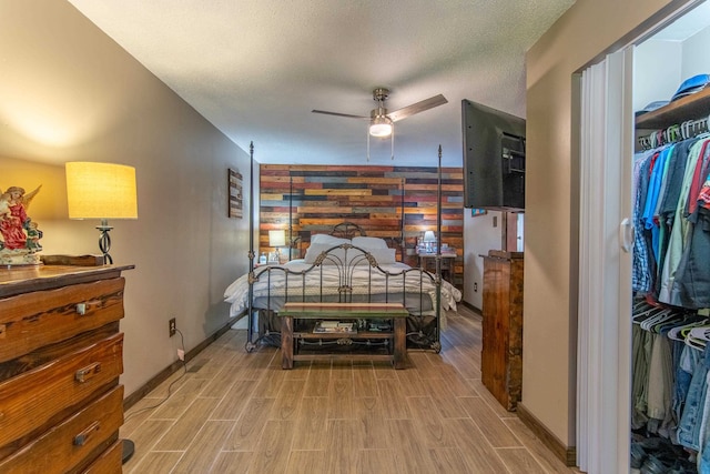 bedroom featuring ceiling fan, a textured ceiling, hardwood / wood-style flooring, a closet, and wooden walls