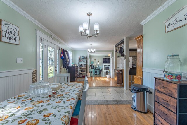 bedroom with crown molding, a notable chandelier, a textured ceiling, and light wood-type flooring