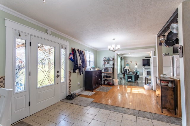 entrance foyer with ornamental molding, a chandelier, a textured ceiling, and light hardwood / wood-style floors