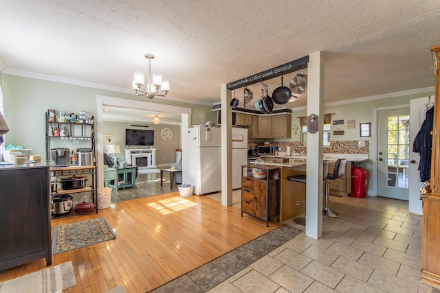 kitchen featuring white fridge, ornamental molding, and light wood-type flooring