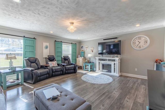 living room with ornamental molding, a textured ceiling, a barn door, and dark hardwood / wood-style flooring