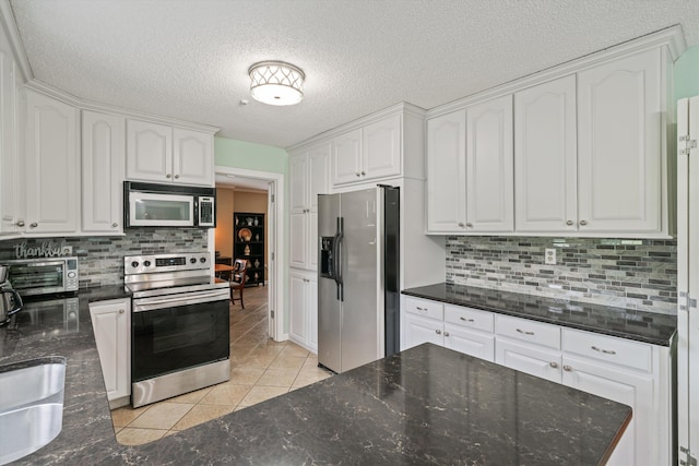 kitchen featuring light tile patterned floors, backsplash, a textured ceiling, white cabinetry, and stainless steel appliances